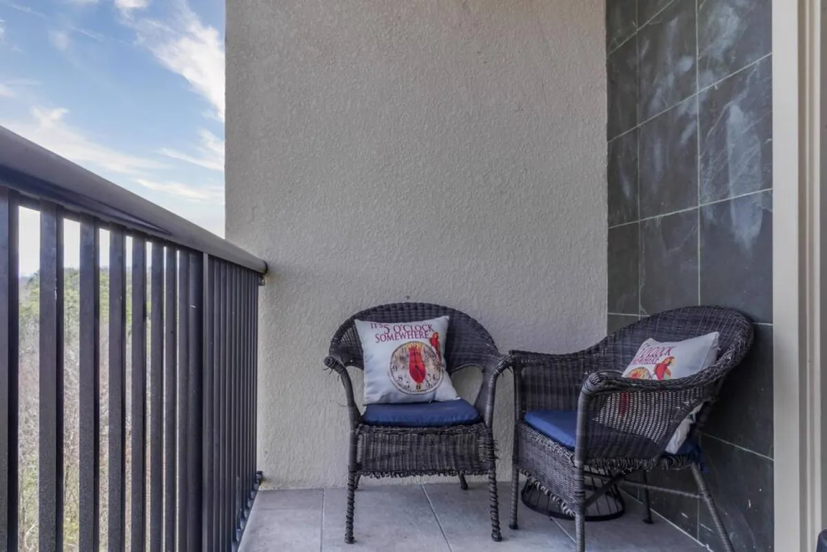 This exterior image features two wicker chairs with decorative pillows placed on a balcony or patio, offering a peaceful vantage point to enjoy the natural surroundings. The setting invites relaxing moments such as sipping coffee, reading a book, or taking in the view, with a clear sense of connection to the outdoors.