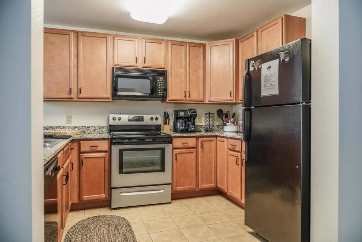 A bright, welcoming kitchen featuring kitchen cabinets, stainless steel appliances, and granite countertops. The space is clearly ready for cooking, baking, and gathering, with everything from a refrigerator to a stove in view. The open layout allows for conversation and interaction, reinforcing the kitchen as a communal hub.