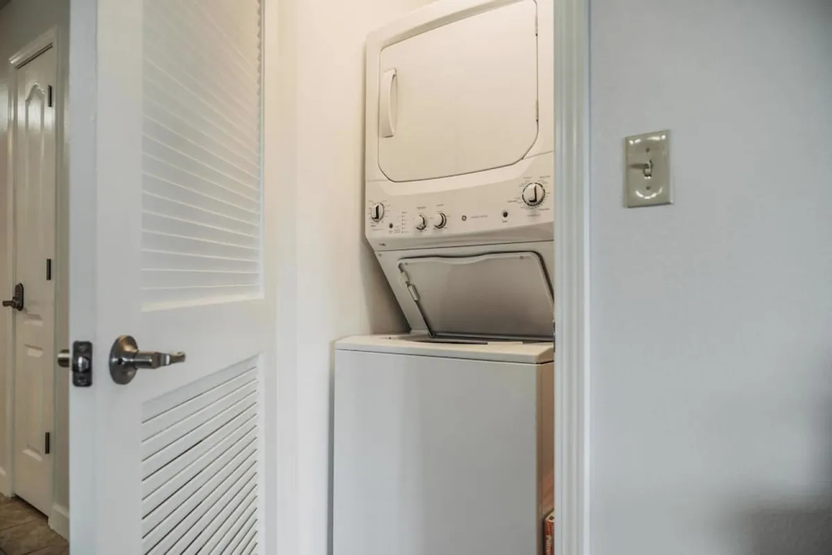 A practical laundry area with a stacked washer and dryer set in a well-lit nook. The area is compact and efficient, emphasizing everyday convenience for guests who want to pack light and feel at home.
