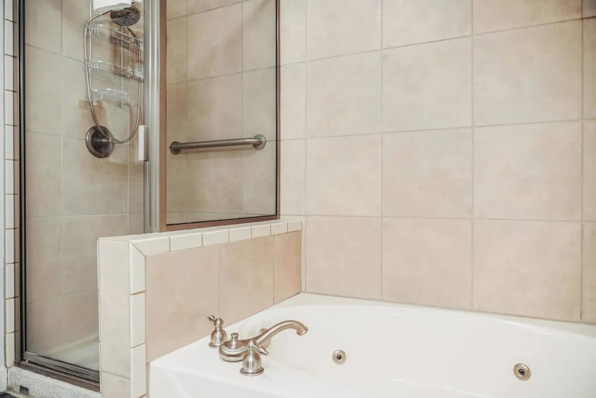 A bathroom featuring a bathtub, shower, and gleaming faucets. The setting is tranquil, with a clean and modern look that suggests a spa-like experience for relaxing baths or invigorating showers.